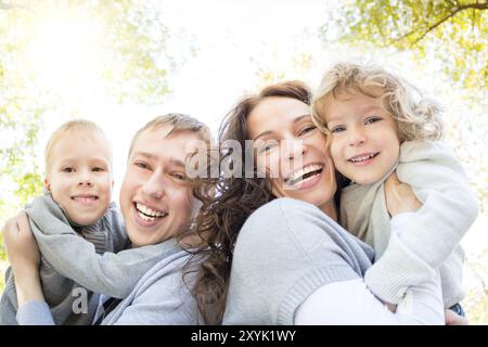 Low angle view portrait of happy family having fun outdoors in autumn park against yellow leaves background. Shot was taken with fisheye lens Stock Photo