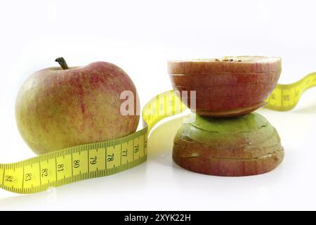 Diet, round apple changes its shape and gets slim waistline, tape measure, isolated on white background Stock Photo