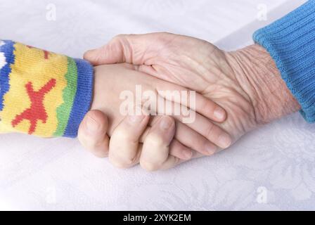 Hand of a child and senior man on white table cloth Stock Photo