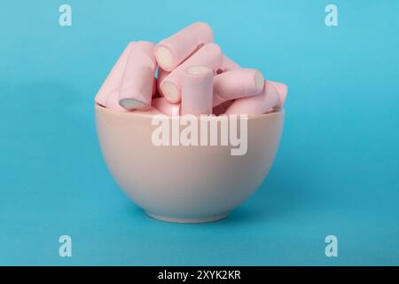 A horizontal image showing a close-up of a pink bowl filled with fluffy marshmallows, with an extra pile positioned on the left. The background is a c Stock Photo