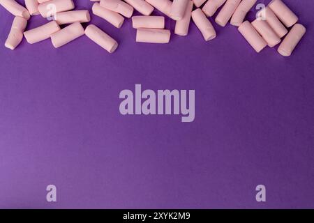 A horizontal photo showing a chaotic arrangement of marshmallows filling the top part of the image. Captured from a bird's-eye view on a vibrant purpl Stock Photo
