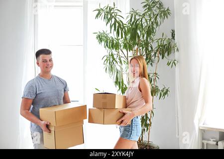 Young happy couple in room with moving boxes at new home Stock Photo