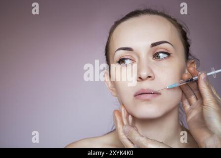 Young pretty woman getting cosmetic injection in the face like a part of the clinic treatment. Medicine, healthcare and beauty concept Stock Photo