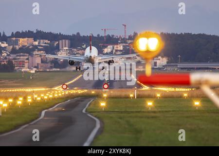 Aircraft of the airline Swiss landing in the evening with illuminated runway. Zurich Airport, Switzerland, Europe Stock Photo