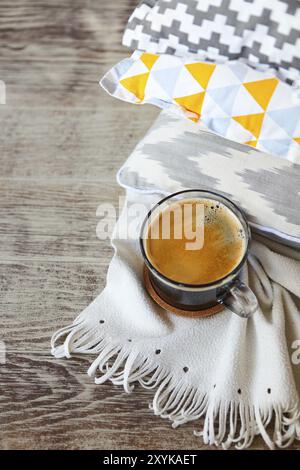 Yellow and grey pillows and cup of coffee on the wall background. Close up Stock Photo