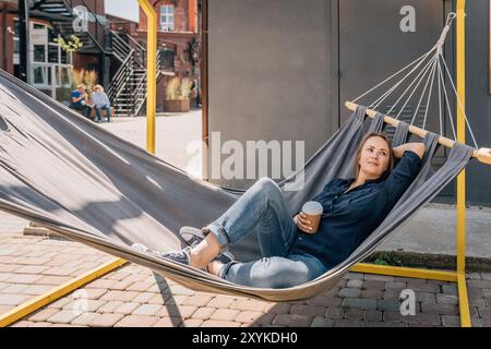 relaxed woman enjoying coffee in an urban hammock Stock Photo