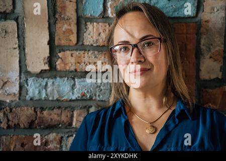 relaxed middle-aged blonde woman against colorful brick wall Stock Photo