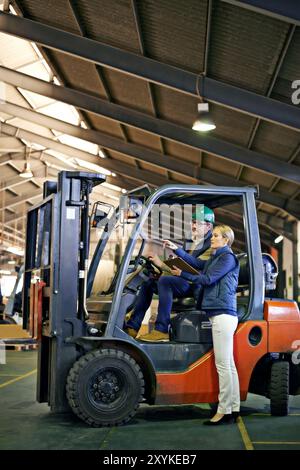 Discussion, warehouse and workers with forklift working on site, loading on dock with Industrial moving vehicle. Teamwork, together or woman with Stock Photo