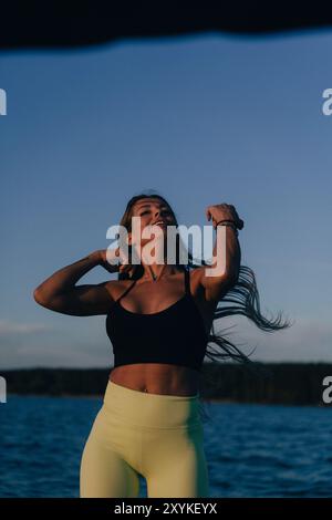 Portrait of happy young woman with blowing hair in front of the sea. Stock Photo