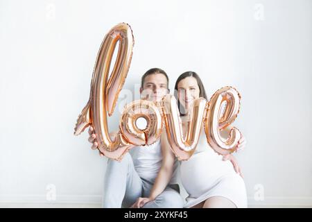 Young happy pregnant woman and man in love on white background. Love and family concept Stock Photo