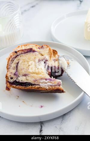 Slice of blueberry cream cheese babka on a white plate with a knife Stock Photo