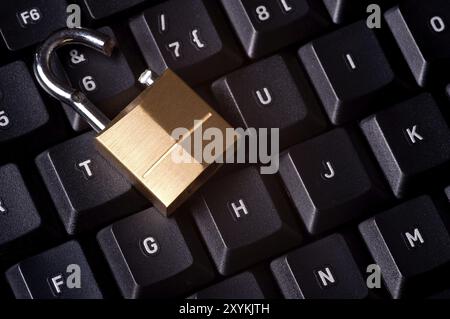 A broken padlock on top a computer keyboard to represent the concept of computer security breach Stock Photo