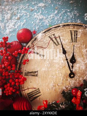 From above of retro wooden clock showing almost midnight placed with various red decorative elements on blue table with white snowflakes Stock Photo