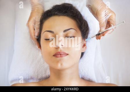 Young pretty woman getting cosmetic injection in the face like a part of the clinic treatment. Medicine, healthcare and beauty concept Stock Photo