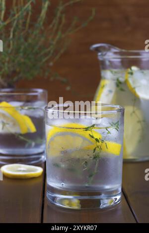 Cool beverage with lemon and thyme, on wooden background Stock Photo