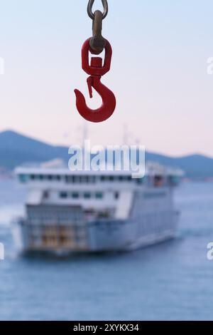Ferry crane hook close-up and a ferry visible in background. Travel, tourism, sea traffic and transportation concepts Stock Photo