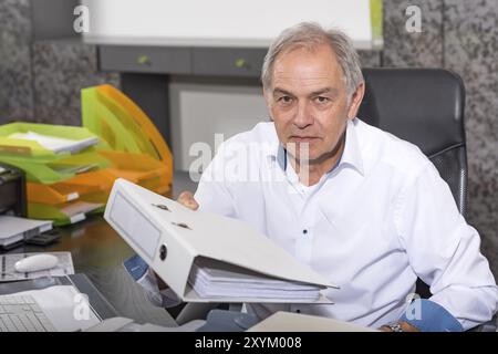 Older man in a white shirt hands over a file folder Stock Photo