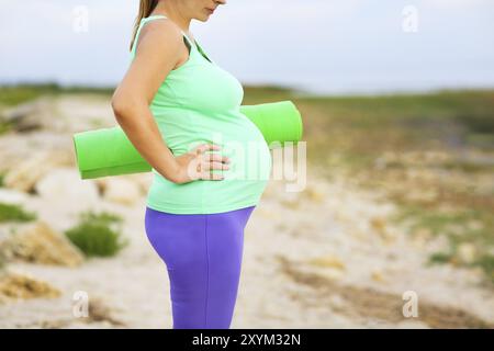 Beautiful pregnant woman doing sport in summer evening outdoors Stock Photo