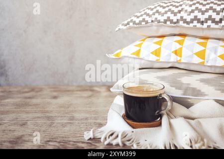 Yellow and grey pillows and cup of coffee on the wall background. Close up Stock Photo