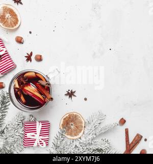 Christmas flat lay top view on gray concrete background with mulled wine glass cup or mug, red gift boxes, decorations, cinnamon sticks, hazelnut, ora Stock Photo
