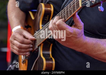 Detail of guitarist's hands and his black electric guitar at an outdoor jazz presentation Stock Photo