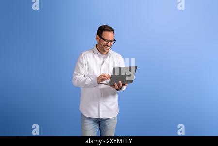 Portrait of handsome entrepreneur checking e-mails over wireless computer on blue background Stock Photo