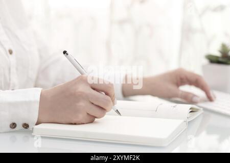 Close up of female hands writing and using computer, high key. Blogger or business concept Stock Photo