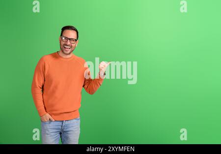 Portrait of happy businessman pointing aside and advertising commercial service on green background Stock Photo
