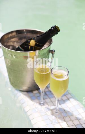 Champagne glasses and bottle in ice bucket near swimming pool. Vacation and romance concept Stock Photo