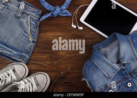 Tablet, earphones, denim clothing and sneakers on the wooden background Stock Photo