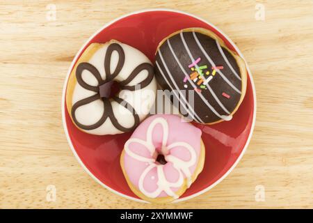 Tasty doughnuts in red plate on wooden board Stock Photo