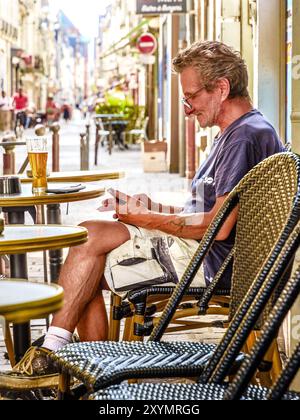 Middle-aged man (worker) at outdoor cafe table looking at smartphone - Tours, Indre-et-Loire (37), France. Stock Photo