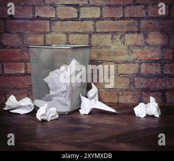 Recycle bin filled with crumpled papers. Brick wall background. Retro style Stock Photo