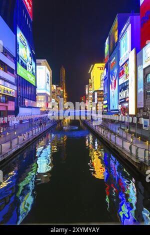 OSAKA, JAPAN, JUNE 23, 2015: Bright illuminated signs on banks of Dotonbori canal at night in Namba district of Osaka, Japan. Vertical Stock Photo