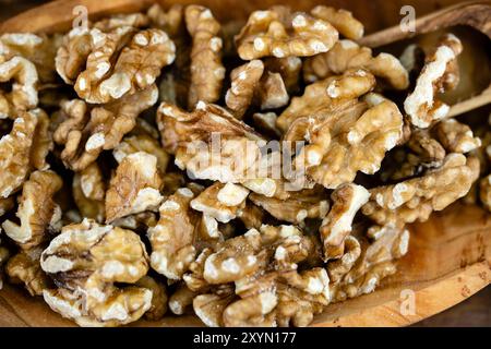 walnut (Juglans regia), cracked walnuts with a wooden shovel on a wooden plate Stock Photo