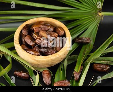 Dates in a wooden bowl on a palm leaf Stock Photo