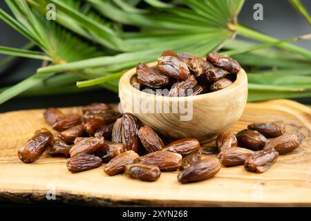 Dates in a wooden bowl with palm leaf Stock Photo