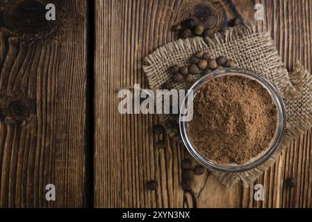 Portion of Allspice powder (detailed close-up shot) on wooden background Stock Photo