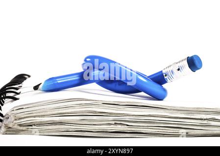 A blue pencil with a blue eraser on the end is bend, and tied in to a knot, and placed on top of a small white notebook Stock Photo