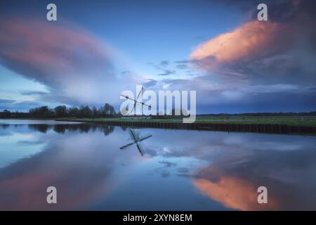 Dramatic stormy sunset over Dutch windmill and river, Groningen, Netherlands Stock Photo