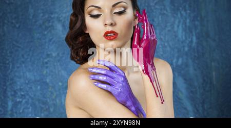 Portrait of a beautiful young woman with bright make up and colored splashes hands Stock Photo