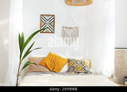 White and beige bedroom in boho style with macrame on the wall Stock Photo