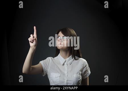 Brunette woman push computer virtual button with finger over black background Stock Photo