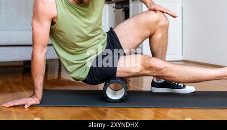 Male athlete doing fitness exercise using foam roller, home workout. Stock Photo