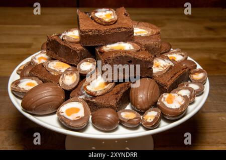 A plate of delicious chocolate cream easter egg brownies, chocolate easter eggs treats on a wooden kitchen table Stock Photo