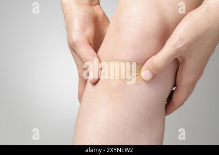 Woman putting an adhesive bandage on her leg Stock Photo