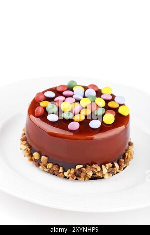 Caramel layered sponge cake with colorful sweet candies and nuts Stock Photo