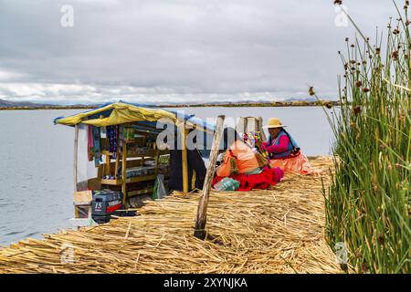 PUNO, PERU, FEBRUARY 1, 2016 : Uru woman wearing traditional cloths buying food and necessary things from a boat market at Uros Floating Island on Lak Stock Photo