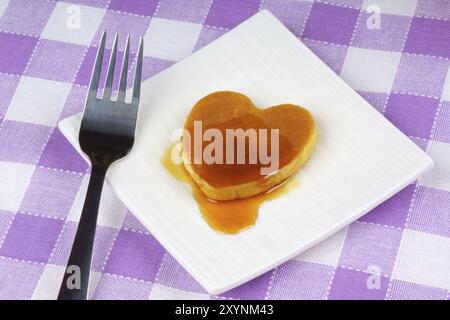 Mini heart-shaped pancake with syrup on a white dish with fork. A perfect breakfast for Valentine's Day Stock Photo