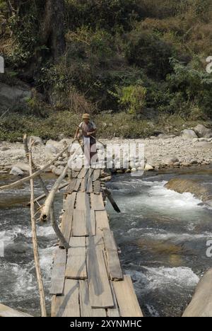 Bhutanese woman passing a dangerous footbridge at Lingmethang (near Mongar), Bhutan, Asia Stock Photo